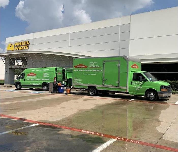 SERVPRO van and box truck in a parking lot in front of a cream building