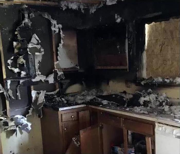 A kitchen covered in soot and smoke damage after a fire disaster